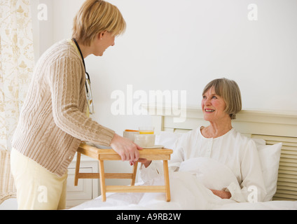 Krankenschwester bringt senior Frau Frühstück im Bett Stockfoto