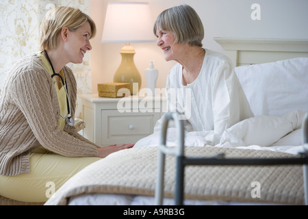 Krankenschwester im Gespräch mit älteren Frau im Bett Stockfoto