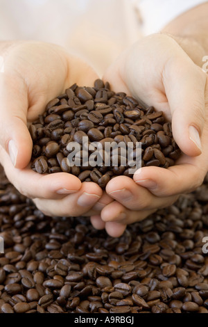 Person, die Handvoll Kaffeebohnen Stockfoto