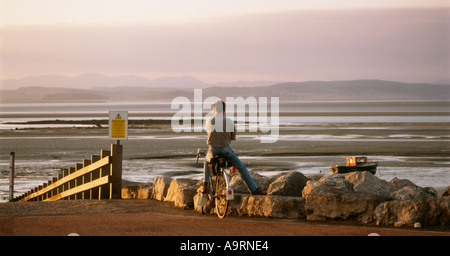 Ein Radfahrer, bewundern Sie die Aussicht bei Sonnenuntergang mit Blick auf Morecambe Bay und den Lake District Stockfoto