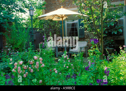 Geschlossene Terrasse außerhalb städtischen Hauses bietet üppige bunt blühenden Garten, Gartenmöbel und Sonnenschirm Stockfoto