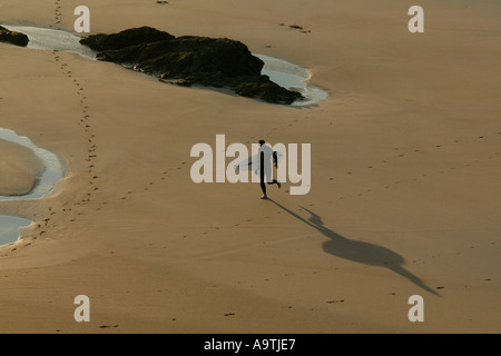 Einsamer Surfer aus Wasser wirft lange Schatten in frühen Abend Stockfoto