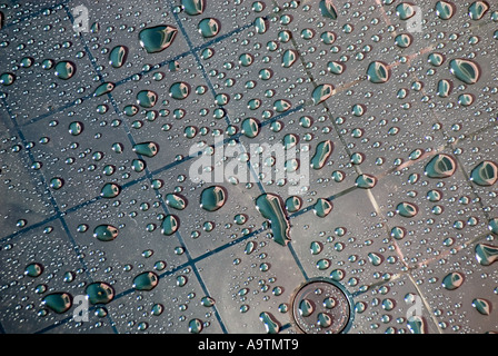 Nahaufnahme eines Teils der abstrakten Anordnung von Regenwassertröpfchen auf Rastermarkierungen auf einem neuen Plastikgartentisch im Hausgarten in Essex England Großbritannien Stockfoto