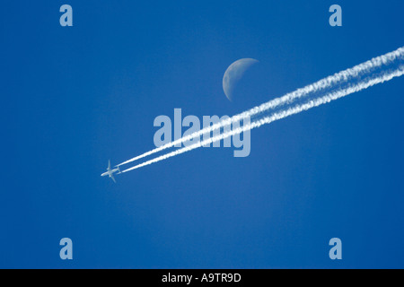 Zwei motorisierten zivilen Passagierflugzeugs hinterlässt Kondensstreifen auf einen blauen Himmel mit Mond, zeigt Stockfoto