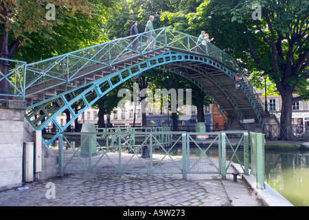 Touristen, die einen Spaziergang über die malerische Passerelle Bichat machen, eine Fußgängerbrücke aus Metall, die den Canal Saint-Martin in Paris, Frankreich, überspannt Stockfoto