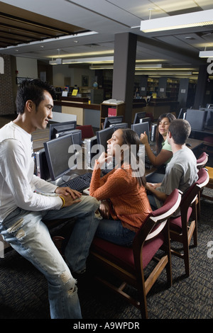 Studenten im Gespräch während der Verwendung von Computern in der Bibliothek Stockfoto