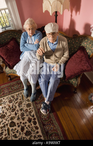 Mürrisch älteres Paar sitzt auf dem Sofa im Wohnzimmer Stockfoto