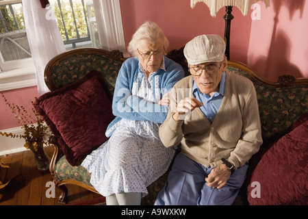 Mürrisch älteres Paar sitzt auf dem Sofa im Wohnzimmer Stockfoto