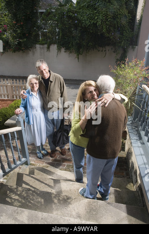 Frau fröhlich umarmt senior woman auf Schritte beim Mann und ältere Frau zu sehen Stockfoto