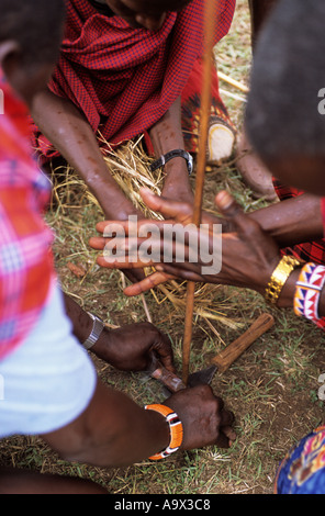 Lolgorian, Kenia. Siria Maasai Moran (junger Krieger) Feuer mit traditionellen Holz Reibung Methode machen. Stockfoto