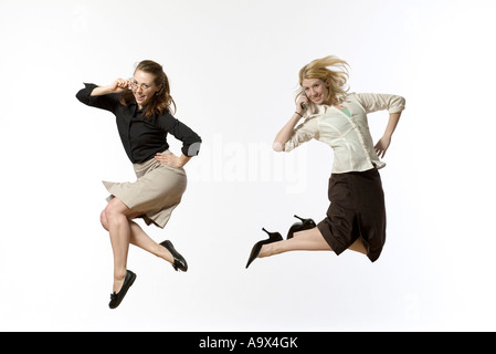 zwei junge Unternehmerinnen springen freudig in die Luft in der konservativen Kleidung Stockfoto