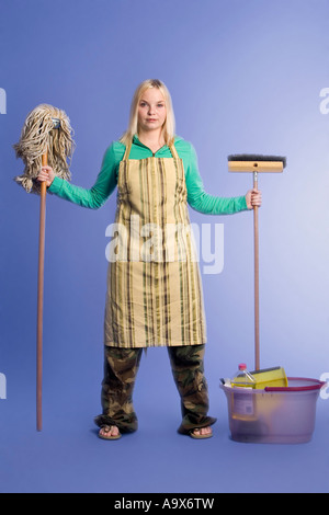 junge Frau mit Haus Reinigung Werkzeuge bereit, um ihre Aufgaben auf.  Sie hat Eimer, Pinsel, Mop und Reinigungsmittel Stockfoto