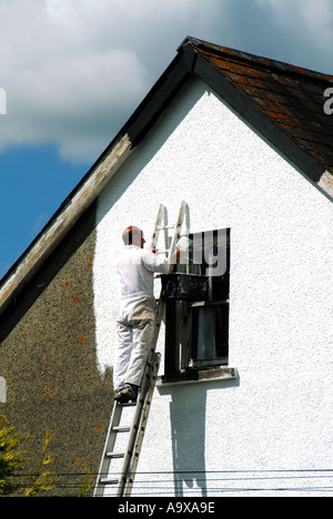 Mann auf der Leiter Verzierung gerendert Wände des Hauses mit weißer Farbe Stockfoto