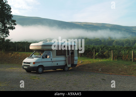 Eine Tour durch den Brecon Beacons National Park am frühen Morgen, bei der sich um den VW-Wohnwagen im Caravan Club herum Nebel aufräumt, der an die Stromleitung von South Wales UK angeschlossen ist Stockfoto