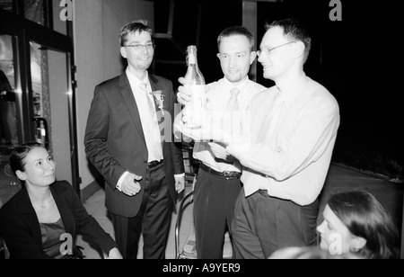 Polen, Lodz, Bräutigam und Hochzeitsgäste mit Champagner Flasche auf Hochzeitsparty (B&W) Stockfoto