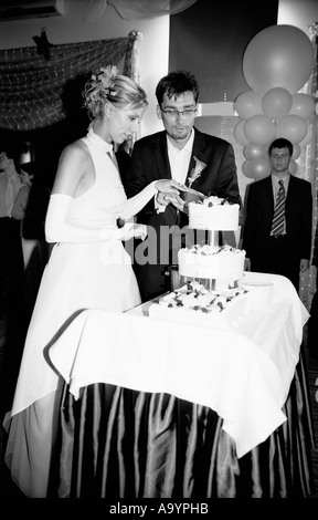 Polen, Lodz, Braut und Bräutigam schneiden Kuchen im Wedding party (B&W) Stockfoto