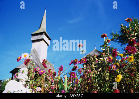 Blick von der Unterseite des Hügels durch den Friedhof Blumen der traditionellen hölzernen Kirche in Botiza, Rumänien Stockfoto