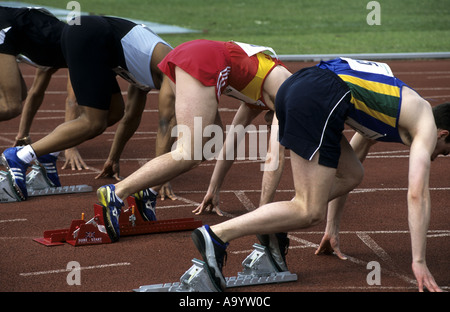 Läufer in Sollposition vor 100m Rennen auf einer Leichtathletikbahn, UK Stockfoto