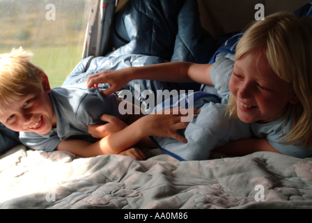 Zwei Kinder in einem Wohnmobil, gemeinsam lachen und im Schlafsack liegend Stockfoto