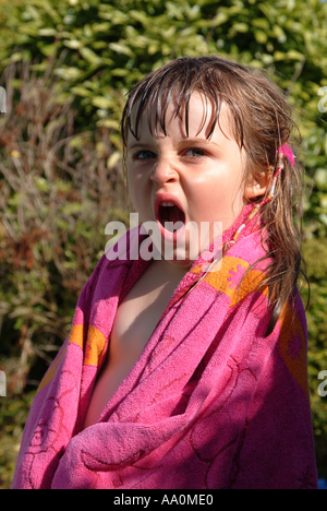 Kleines Mädchen in ein Handtuch gewickelt und Gähnen Stockfoto