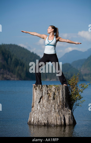 Frau beim Yoga auf Baumstumpf Stockfoto