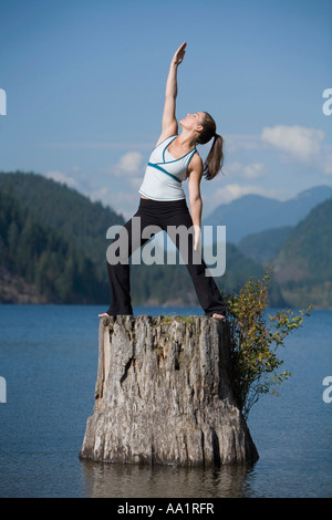 Frau beim Yoga auf Baumstumpf Stockfoto