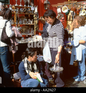 Chinesische Frauen kaufen Silber Antik stall in Portobello Road Market London, England, UK KATHY DEWITT Stockfoto