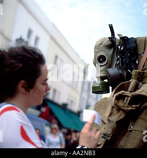 Eine junge Frau, die Prüfung einer Weltkrieg Gasmaske zum Verkauf in Portobello Road Market Notting Hill Gate West London England UK Stockfoto