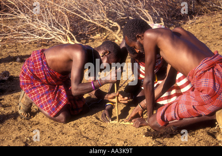 Drei Samburu Männer machen, nördlichen Kenia Ostafrika sie feuern reiben ihre Firesticks zusammen Stockfoto