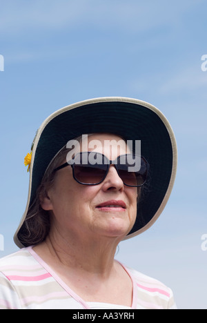 Eine ältere Dame trägt Sonnenbrille und Sonnenhut. Stockfoto