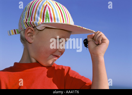 Kleiner Junge vier Jahre alt, ein schwarzer Käfer auf seiner Hand zu betrachten Stockfoto