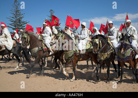 Reiter in weißen Gewändern mit roten Sterne Flaggen am Strand Essaouira, Marokko, Nord AfricaAfrica Stockfoto