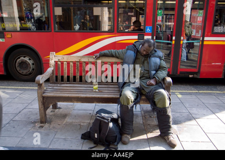 Obdachloser Einschlafen auf einer Bank mit einem Glas Gin Tonic auf seiner Seite, Oxford Street, London, UK Stockfoto