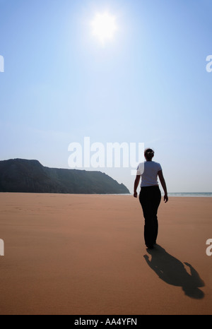 Junge Frau, die zu Fuß am Strand von Three Cliffs Bay auf der Gower-South-Wales Stockfoto