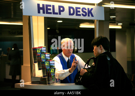 Ein älterer Mann gibt Anweisungen an einen jungen asiatischen Mann bei einem Help Desk am domestic Terminal im Flughafen Auckland New Zealand Stockfoto