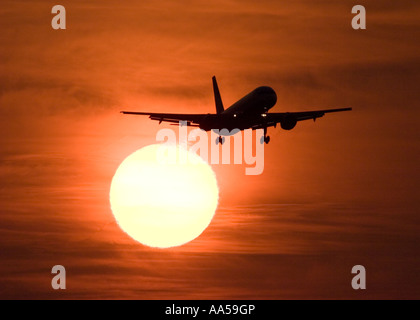 Silhouette einer Boeing 757 Verkehrsflugzeug, die Landung am Flughafen London Heathrow gegen eine große goldene Sonne bei Sonnenuntergang Stockfoto