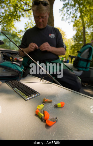 PROFESSIONELLES ANGELN ANGLER SCOTT PETERS BEREITET EINE ANGELSCHNUR BEIM SITZEN IN SEINEM BOOT MIT GELB UND ORANGE PLATINEN Stockfoto