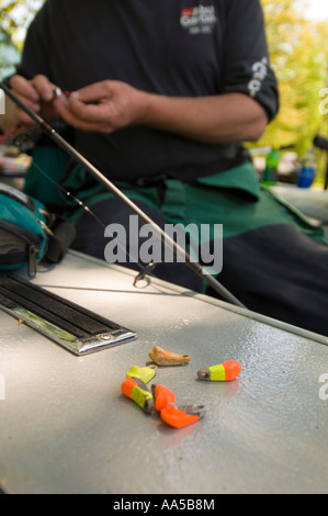 PROFESSIONELLES ANGELN ANGLER SCOTT PETERS BEREITET EINE ANGELSCHNUR BEIM SITZEN IN SEINEM BOOT MIT GELB UND ORANGE PLATINEN Stockfoto