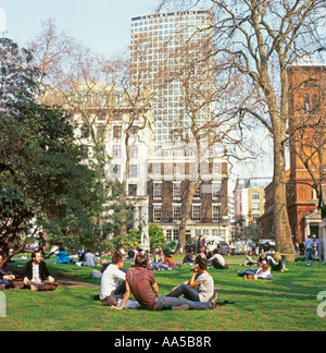 Büroangestellte entspannend in Soho Square zur Mittagszeit mit Centrepoint in der Ferne, London, UK Stockfoto
