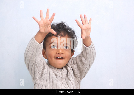 Kleine Indianerjunge von zweieinhalb Jahren frech und lächelnden Händen angehoben tragen weiße Pullover Stockfoto
