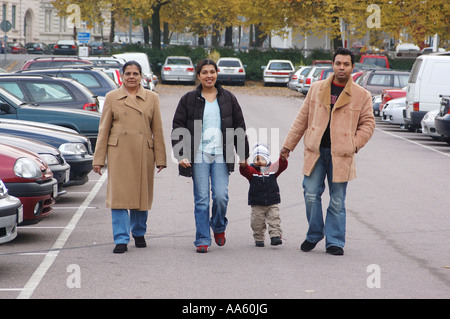 Indischer Junge, der auf dem Parkplatz mit Eltern und Großmutter läuft, die alle Winterkleidung tragen - HERR# Stockfoto