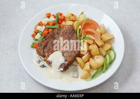 ANG103927 Gegrillte Lende vom Schwein mit würzigen Bratkartoffeln serviert gedünstetes Gemüse Karotten Bohnen Stockfoto