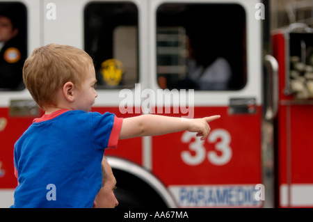 Kleiner Junge, der auf den Schultern seines Vaters sitzt, zeigt, wie ein Feuerwehrauto während der Parade zum St. Patrick's Day in San Diego, Kalifornien, USA vorbeifährt Stockfoto