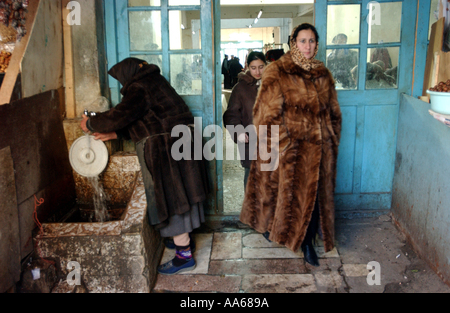 Baku Aserbaidschan 11. Januar 2003 Azeribajiani Frauen tragen schwere Pelzmäntel kommen aus einem Markt, wo Vvndors ihre Früchte verkaufen, Stockfoto