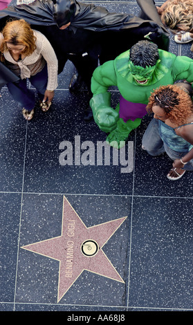 Männer in Superhelden-Kostümen unterhalten weibliche Touristen auf dem Walk of Fame auf dem Hollywood Boulevard in Hollywood, Kalifornien, USA Stockfoto