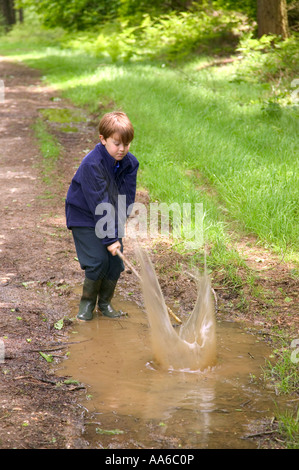 Junge Spaß Spritzwasser in einer schlammigen Pfütze im Wald Stockfoto