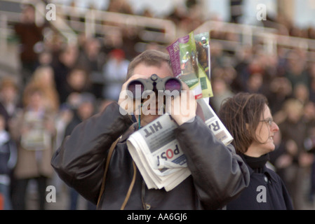 Mann vierzig Blick durch ein Fernglas bei Pferd Rennen Treffen im Sandown Park Stockfoto