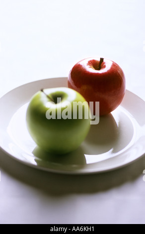 "Grüner Apfel und roter Apfel, weißer Teller, Fokus auf rot" Stockfoto