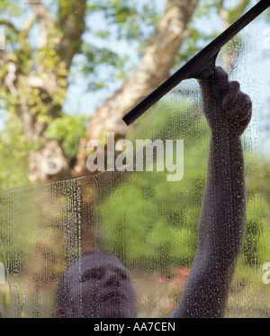 Fenster Reiniger Mann Reinigung Fenster nach außen abwischen Seifenlauge mit Rakel durch Glas von innen gesehen Stockfoto