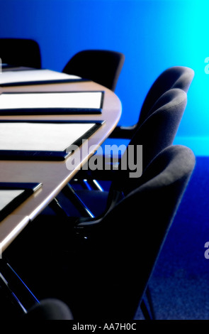 Schwarze Stühle und Lederblotter auf einem Holztisch in einem leeren Sitzungssaal Stockfoto
